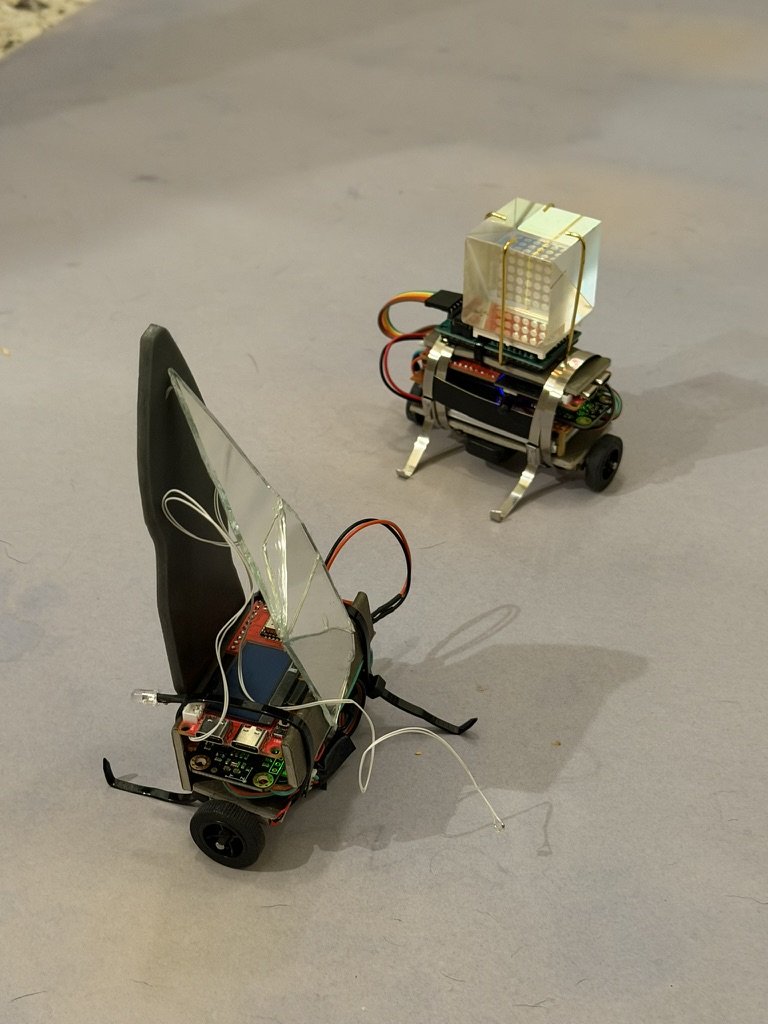The two Love Robots together, showing their cable-tie legs and wires